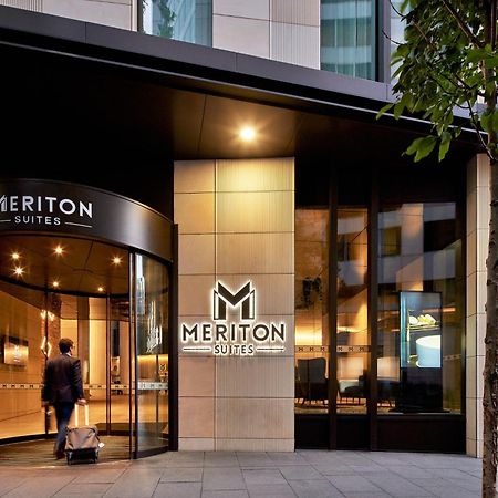 Meriton Suites Sussex Street, Sydney Buitenkant foto The photo shows the entrance of a hotel or suite establishment named "Meriton Suites." The entrance features a revolving door and a large, illuminated sign with the name "MERITON SUITES." The facade is modern and sleek, with a combination of glass an