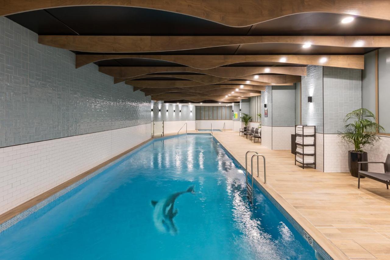 Meriton Suites Sussex Street, Sydney Buitenkant foto The photo shows an indoor swimming pool. The pool features clear blue water, and there is a dolphin swimming in it. The surrounding area has a modern design with curved wooden beams on the ceiling, and the walls are tiled in light colors. There are a