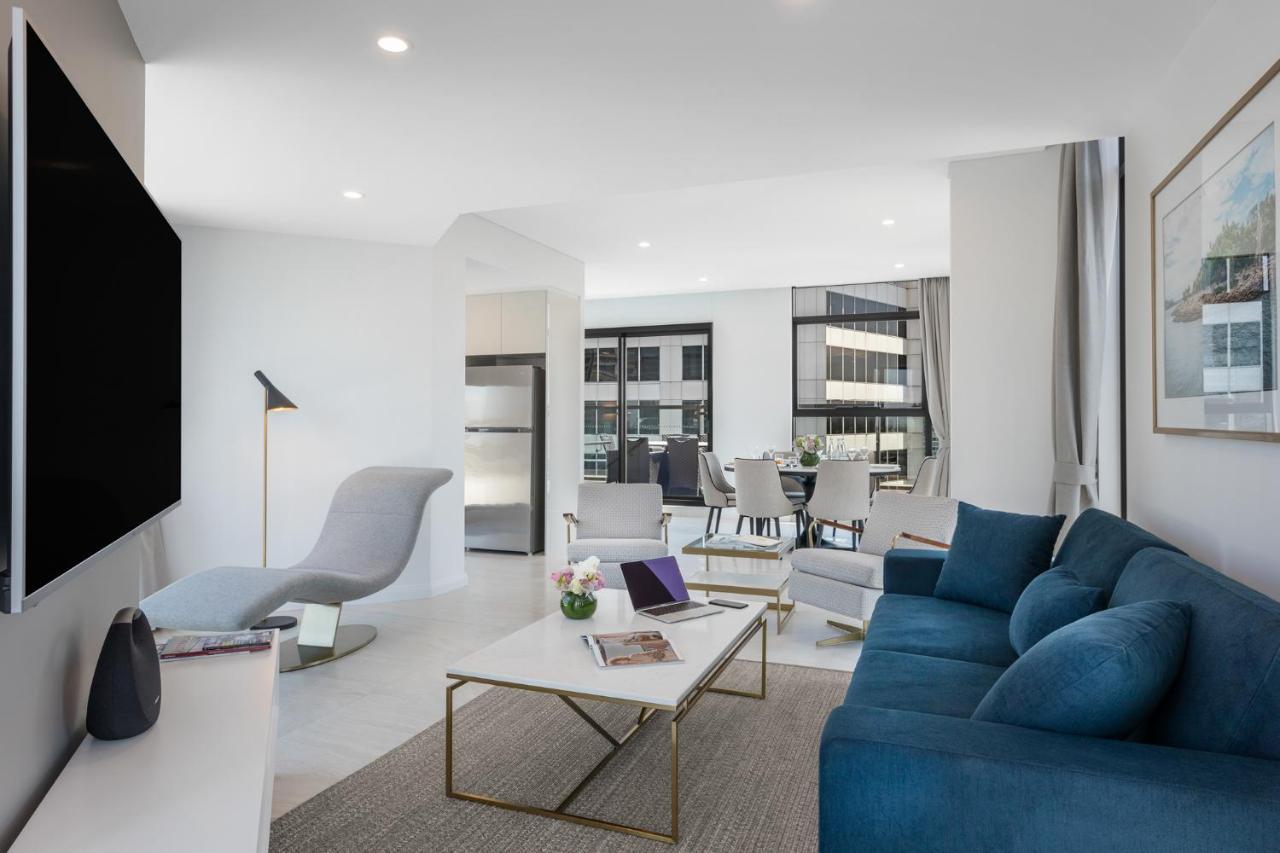 Meriton Suites Sussex Street, Sydney Buitenkant foto The photo shows a modern living space that features a bright and stylish interior. Key elements include:

- A sleek blue sofa and a light gray lounge chair, providing comfortable seating.
- A coffee table with a minimalist design, positioned in front