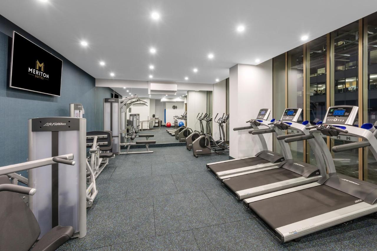 Meriton Suites Sussex Street, Sydney Buitenkant foto The photo shows a modern gym space. It features various exercise equipment, including several treadmills and elliptical machines positioned along one side. On the other side, there are weight machines and additional fitness equipment. The gym has a c
