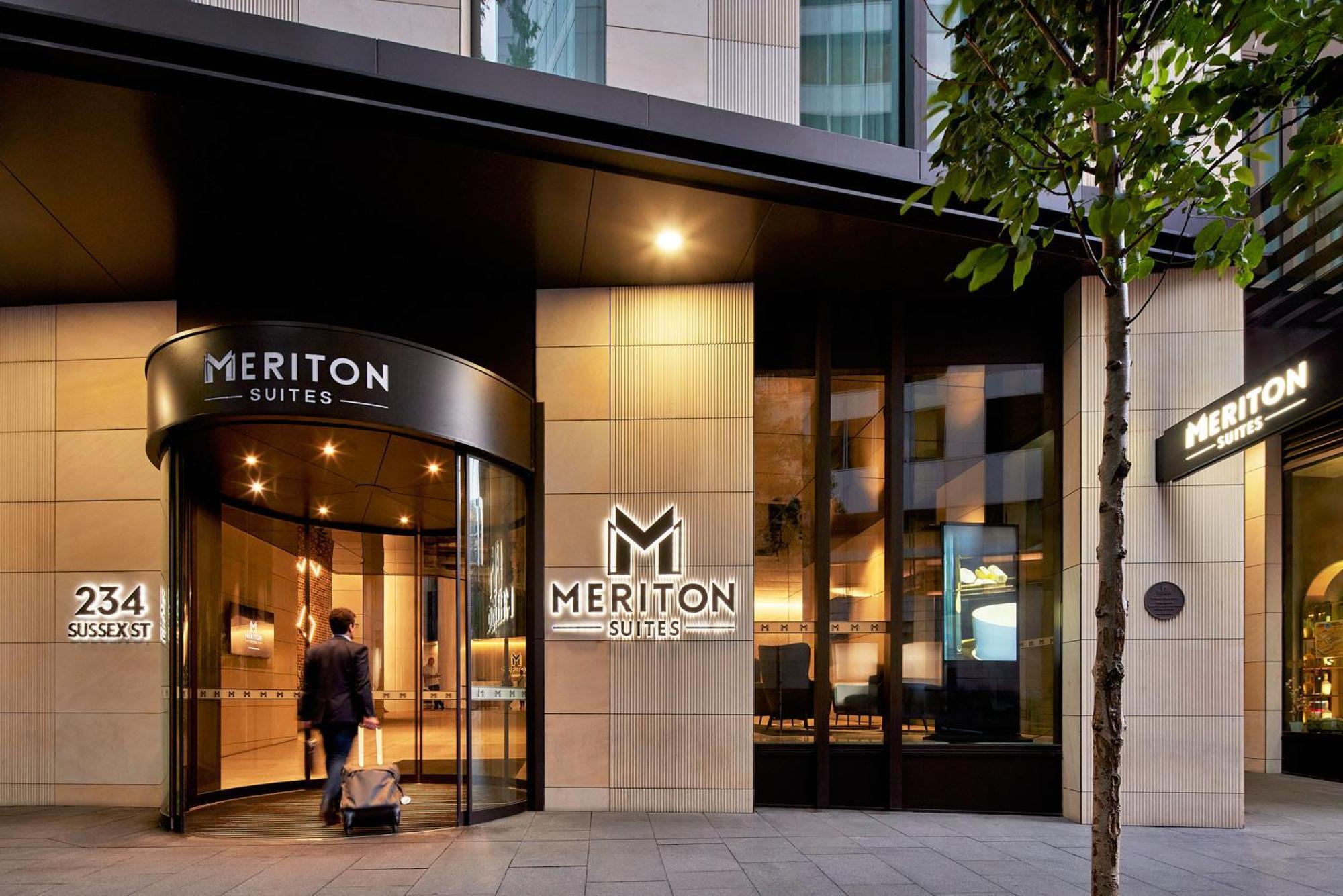 Meriton Suites Sussex Street, Sydney Buitenkant foto The photo shows the entrance of a hotel or suite establishment named "Meriton Suites." The entrance features a revolving door and a large, illuminated sign with the name "MERITON SUITES." The facade is modern and sleek, with a combination of glass an
