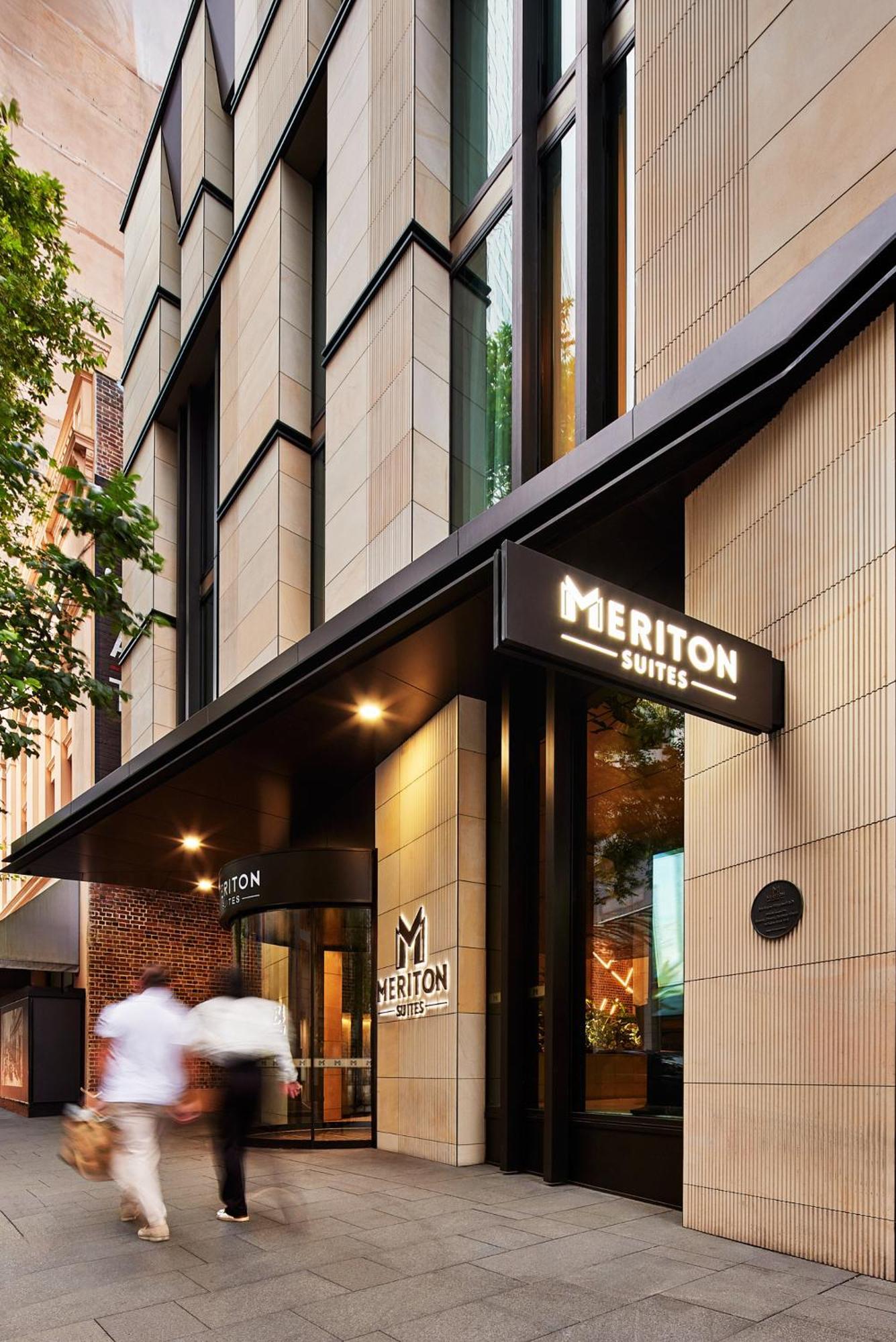 Meriton Suites Sussex Street, Sydney Buitenkant foto The photo shows the exterior of a building with the signage for "Meriton Suites." The entrance features a modern design, with sleek architectural elements and large windows. The entrance is highlighted by a prominent awning and illuminated signs, ind